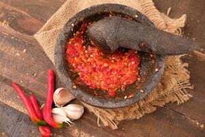 Sambal is a typical Indonesian sauce and seasoning from Java Island made from red chilies, garlic, tomatoes, shrimp paste, and shallots. fresh chili sauce on a mortar photo