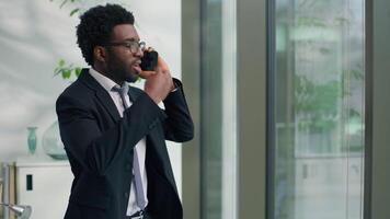 Angry mad stressed African American business man talking arguing mobile phone call problem discuss in office ethnic rage furious businessman male guy employer say argument quarrel looking in window video