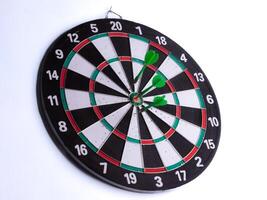 Dartboard with three green darts hitting bullseye on white isolated background. Target accuracy, business goal, marketing strategy, precision and success concept. photo