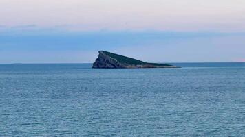 A stunning view of a distinctive island surrounded by calm, tranquil ocean waters during the beautiful dusk hour photo