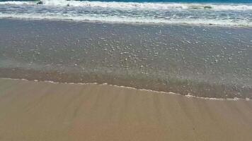 Experience the serene beauty of gentle ocean waves lapping onto a sandy beach beneath vast, clear blue skies photo
