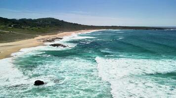 Breathtaking aerial shot beautifully showcasing a pristine beach and rolling turquoise waves beneath clear skies photo