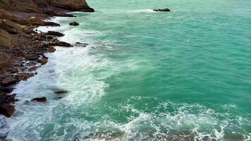 A beautiful and tranquil coastal scene showcasing turquoise waters with rocky cliffs beneath a cloudy sky above photo