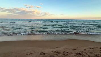 A breathtaking view of a beautiful sunset casting vibrant colors over calm ocean waves lapping softly at a sandy beach photo