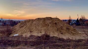 A vast and large mound of soft sand with a stunning vibrant sunset and fluffy clouds in the background sky photo