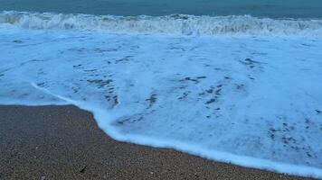 The peaceful ocean waves gently wash over the sandy beach as the sun sets under a beautiful dusk sky photo