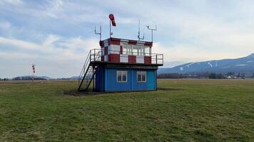 A vibrant air traffic control tower, beautifully designed, surrounded by lush open fields and a stunning clear blue sky photo