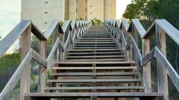 A wooden stairway leads to a modern concrete tower, surrounded by lush greenery that enhances the scenic view photo