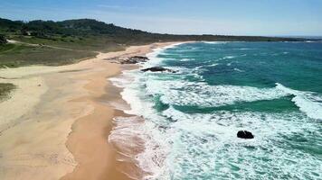 Enjoy a breathtaking aerial view of a tranquil beach with gentle waves and lush green hills surrounding it photo