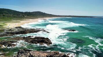 A truly breathtaking and picturesque view of the beach featuring crashing waves, rocky shores, and lush greenery photo