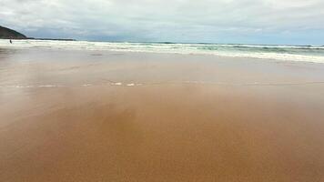 Imagine a tranquil beach scene showcasing soft golden sand and gentle ocean waves rolling in beneath a cloudy sky photo