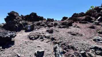 Embarking on an adventure through a volcanic landscape with rocky terrain and clear blue skies reveals natures beauty photo
