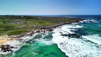 An aerial view shows a dramatic coastline with clear turquoise waters and lush, vibrant green vegetation photo