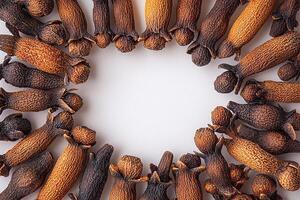 Dried clove spices arranged in a circular pattern on a white surface photo