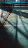 Padel court serenity captured in the interplay of shadows and sunlight highlighting the net texture photo