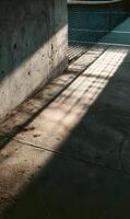 Sunlight casts dynamic shadows on a concrete wall creating an interplay of light and shadow contrasting textures photo
