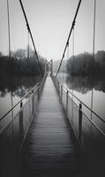Suspension bridge over tranquil waters evokes peace and reflection in monochrome timeless nature scenery photo