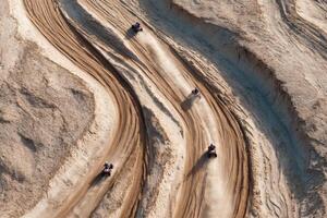 ATVs zoom across winding sandy tracks in a desert area, creating dust clouds as they race under bright daylight photo