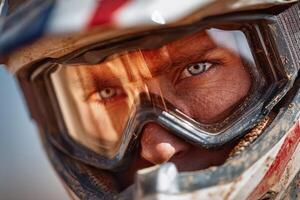 A motocross rider captures the essence of determination with intense blue eyes framed by a helmet and goggles amid race dust photo
