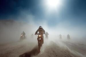 Riders navigate through a dusty landscape on motorcycles, surrounded by a cloud of dust kicked up by their wheels under the bright sun photo