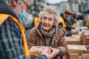 An elderly woman joyfully accepts a food package from a volunteer at a community distribution event on a chilly day photo