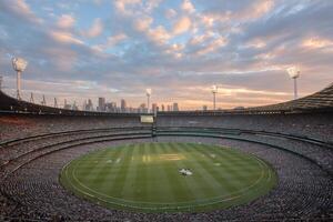Many spectators fill the stands at Melbourne Cricket Ground, cheering for their teams during a thrilling cricket match at sunset photo