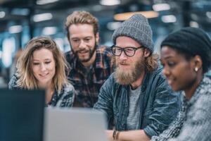 A diverse group of young adults are engaged in collaborative discussions while working on projects at a sleek office space during the day photo