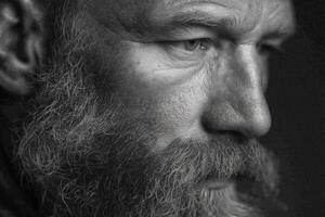 An elderly man with a thick beard gazes thoughtfully into the distance, his weathered features reflecting wisdom and experience photo