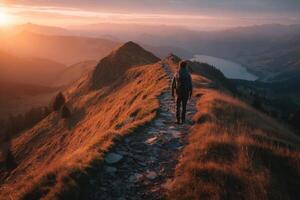 A hiker walks on a rocky path at sunset, surrounded by glowing hills and expansive views of distant mountains and lakes photo