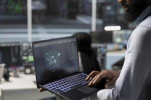 Close up of data center engineer using laptop to implement AI virtualization frameworks, improving resource allocation. Server hub worker does artificial intelligence predictive analysis on notebook photo