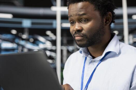Close up of programmer in server room uses laptop to implement and manage data backup solutions. Data center IT specialist identifying and resolving technical glitches, ensuring efficient recovery photo