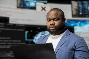 Young black IT engineer working in a digital environment with programming language and data science algorithm. Specialist reviews code development, automation and innovation. Coding life. photo