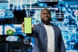 Black businessman using advanced technology and green screen on phone, exploring data science, automation and AI brain in a digital data visualization environment. Machine learning. photo