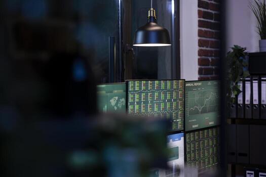 tranquilo, oscuro oficina con múltiple monitores mostrando gráficos, creando un atmósfera de anticipación para próximo comercio sesión. profesional comercio espacio de trabajo, arreglado para noche cambio empleados. foto