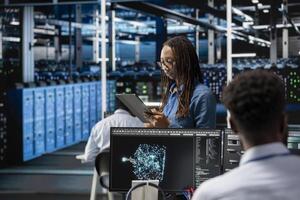Data center specialist using AI deep learning algorithms on tablet to analyze large datasets. Server farm programmer using artificial intelligence on device to recognize patterns in facility data photo