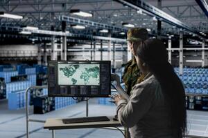 Team of military experts in data center examining mission coverage zones on global mapping software. Army units in server farm confirming strategic priorities using interactive geographic display photo