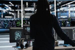 Data center engineer uses AI visualization tool on laptop to oversee automated repetitive tasks. Worker adapting server systems based on data analytics graphs using notebook device photo