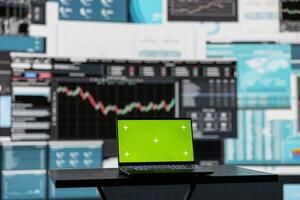 In a business related space, laptop display shows green screen to help with strategy planning with financial data. Representing modern artificial intelligence and productivity for growth. photo