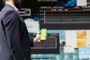 Professional man looks at green screen and explores strategy planning with insight and financial data in a digital workspace. Representing modern business intelligence and productivity. photo