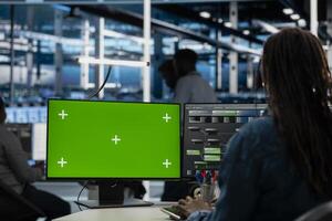 Engineer working on isolated screen desktop PC in data center housing storage infrastructure. IT professional using chroma key computer display in server hub workspace filled with networking tech photo