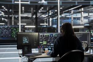 Data center engineer uses AI visual programming to oversee automated repetitive tasks minimizing manual intervention. Worker adapting server systems based on data analytics graphs photo