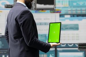 Male administrator uses green screen tablet to explore new growth strategy with insight and analytics in a digital workspace. Representing modern business intelligence and productivity. photo