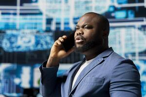 Black tech specialist talking on a smartphone call in an AI powered environment, representing predictive algorithms and machine learning systems. Working on automation and innovation. photo