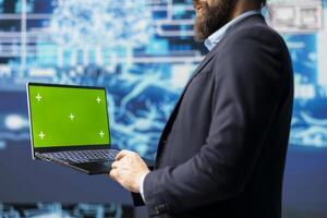 Surrounded by data and neural networks systems, male IT engineer navigates artificial intelligence with a chroma key on laptop. Using automation for modern strategy and innovation. photo