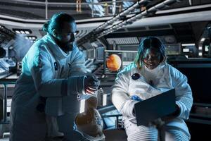 Teamworking astronauts use tablet to ensure safe operation during long distance space travel to Mars. Orbital station crew monitors system stability during cosmic journey to red planets photo