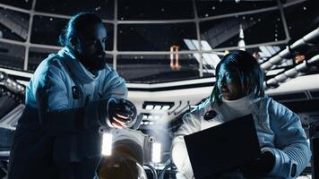 Team of astronauts running data analysis on laptop before stepping out outside space station. Teamworking cosmonaut verifying mission parameters on notebook after landing on planet photo
