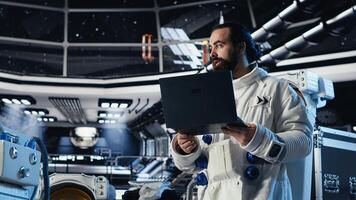 Astronaut reviewing onboard analytics on laptop before stepping out for scheduled operations outside space station. Cosmonaut verifying mission parameters after landing on alien planet photo