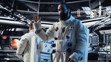 Astronaut waves hand during videocall with Earth command center while aboard spacecraft, sharing mission update. Cosmonaut salutes researchers during communication link to ground center photo