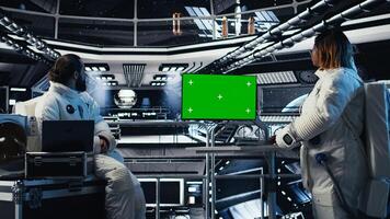 Astronauts checking human expansion in space mission logs on isolated screen monitor. Teamworking cosmonaut looking at mockup display during mankind survival expedition photo