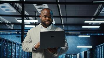 Data center engineer analyzing equipment performance, resolving technical issues. Server farm employee doing job tasks, overseeing operations, implementing efficiency optimizations, camera B photo